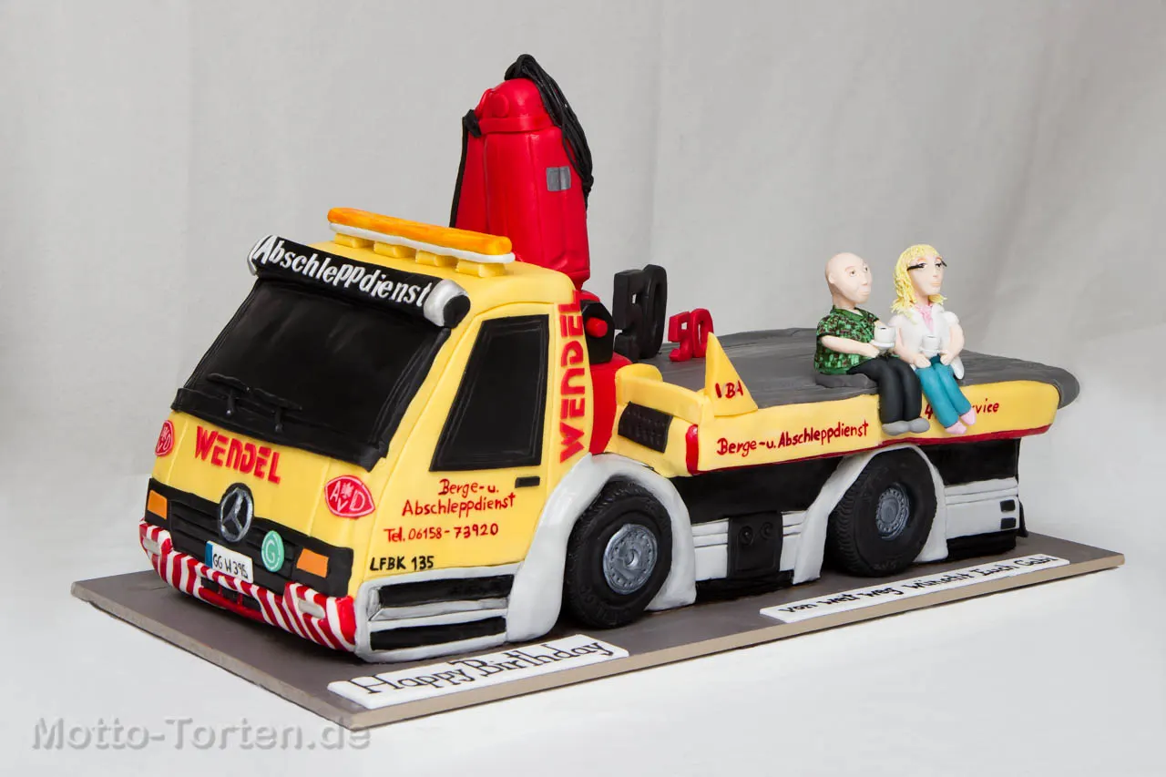 3D-Torte in Form eines roten Mercedes-Abschleppwagens mit Kran, auf der Ladefläche zwei handmodellierte Figuren beim Kaffee