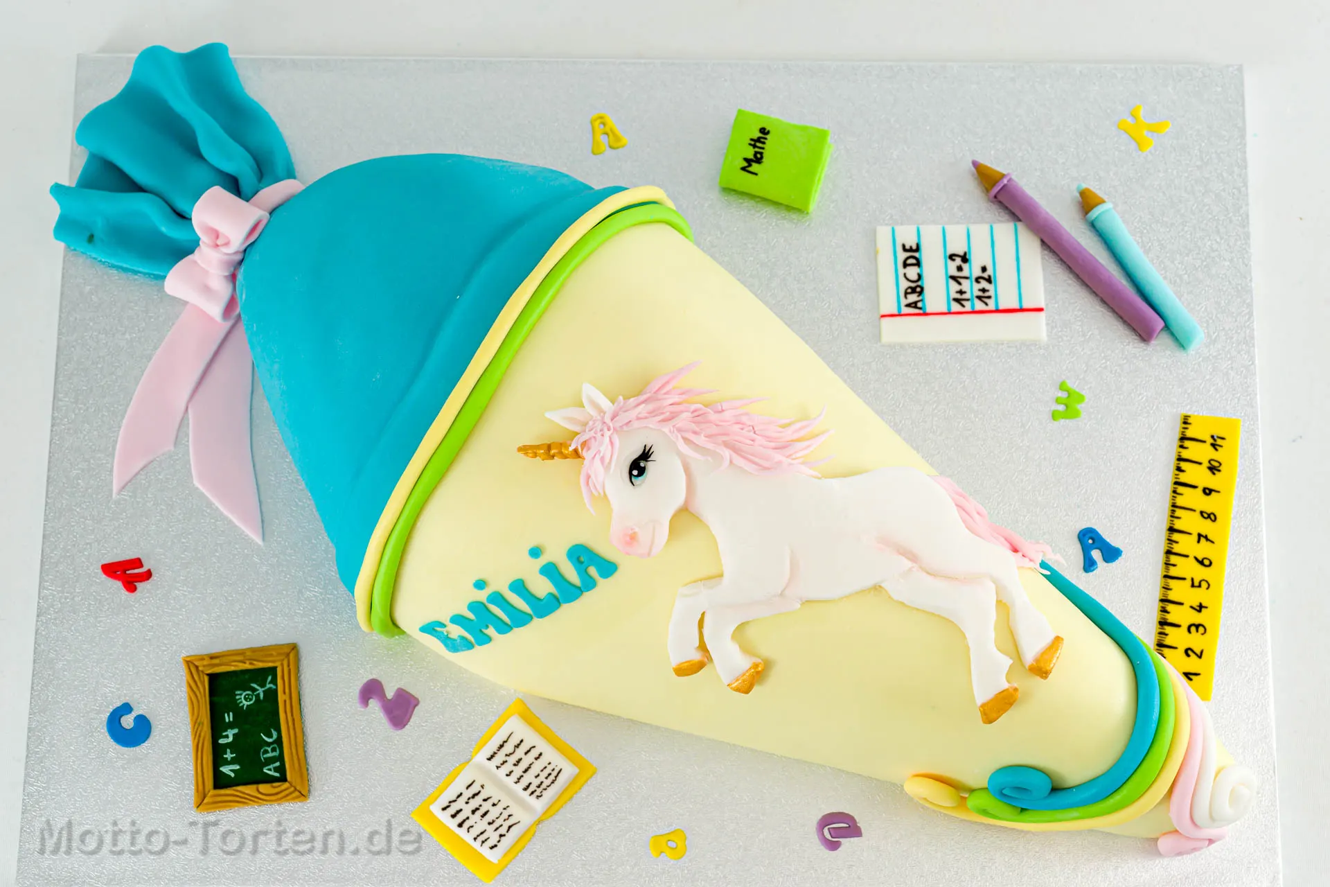 Schultüte als Torte in Creme und Türkis mit einem weißen Einhorn mit rosa Mähne und goldenen Hufen