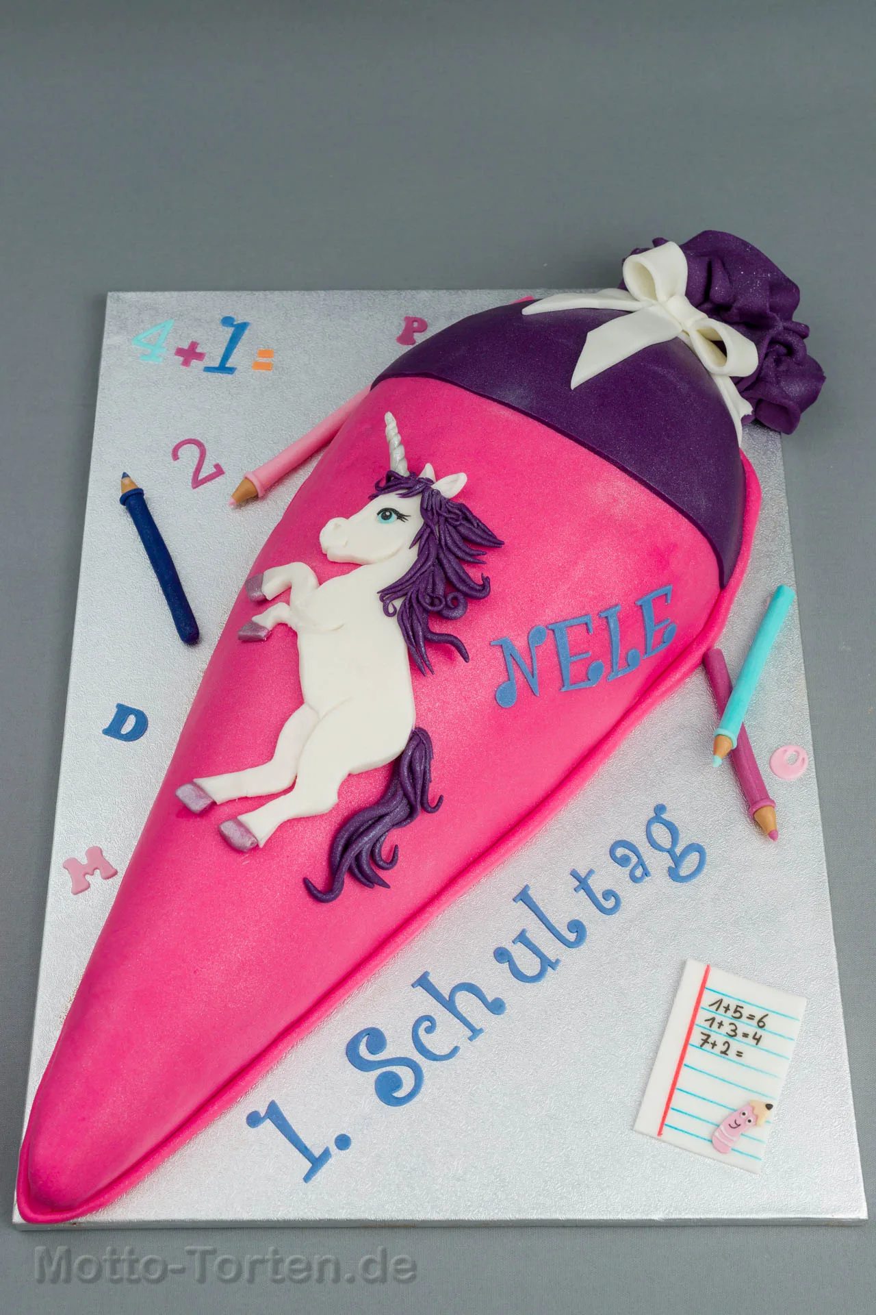 Schultüte als Torte in Pink und Violett mit einem weißen Einhorn aus Fondant und dem Namen Nele