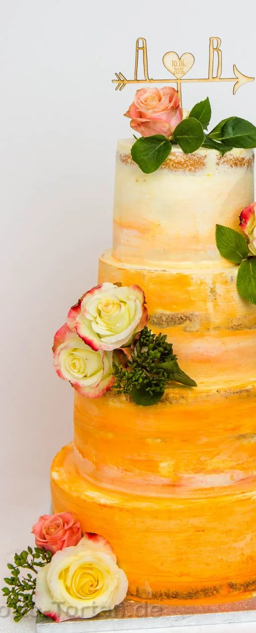 Vierstöckige Hochzeitstorte in Buttercreme mit Farbverlauf von Apricot zu Creme, dekoriert mit echten Rosen und einem hölzernen Tortenaufsatz