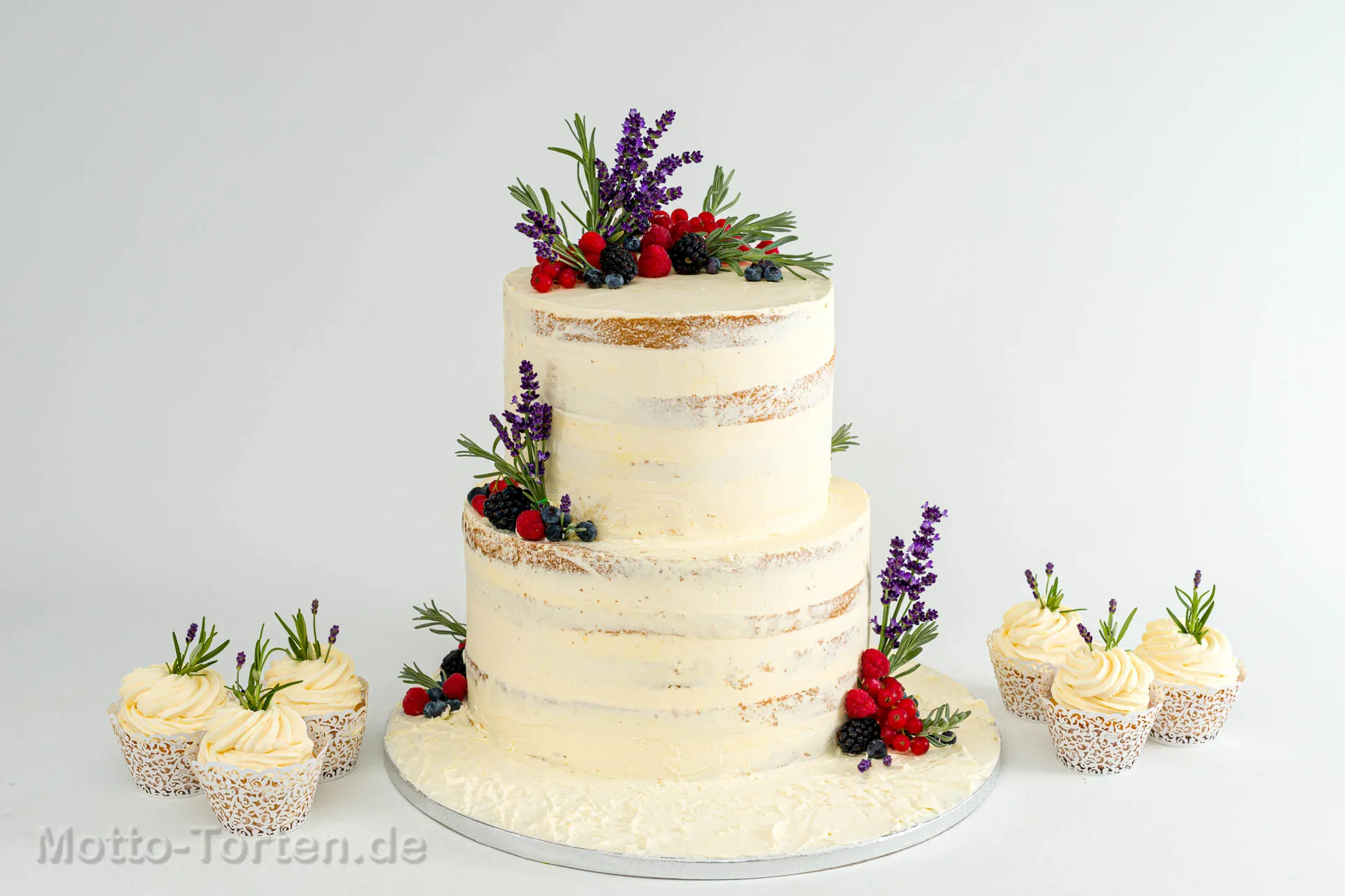 Cremefarbene Hochzeitstorte mit essbarem Blattgold, frischen Beeren und Macarons