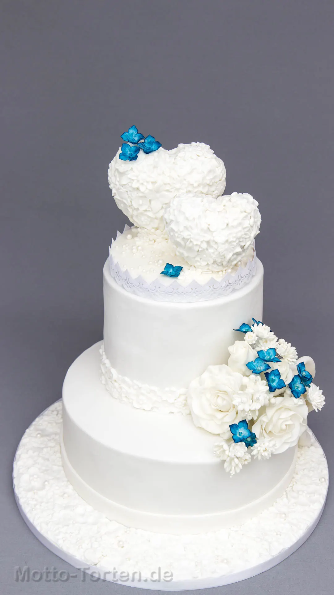 Hochzeitstorte mit zwei Herzen in einem Meer aus Zuckerblüten