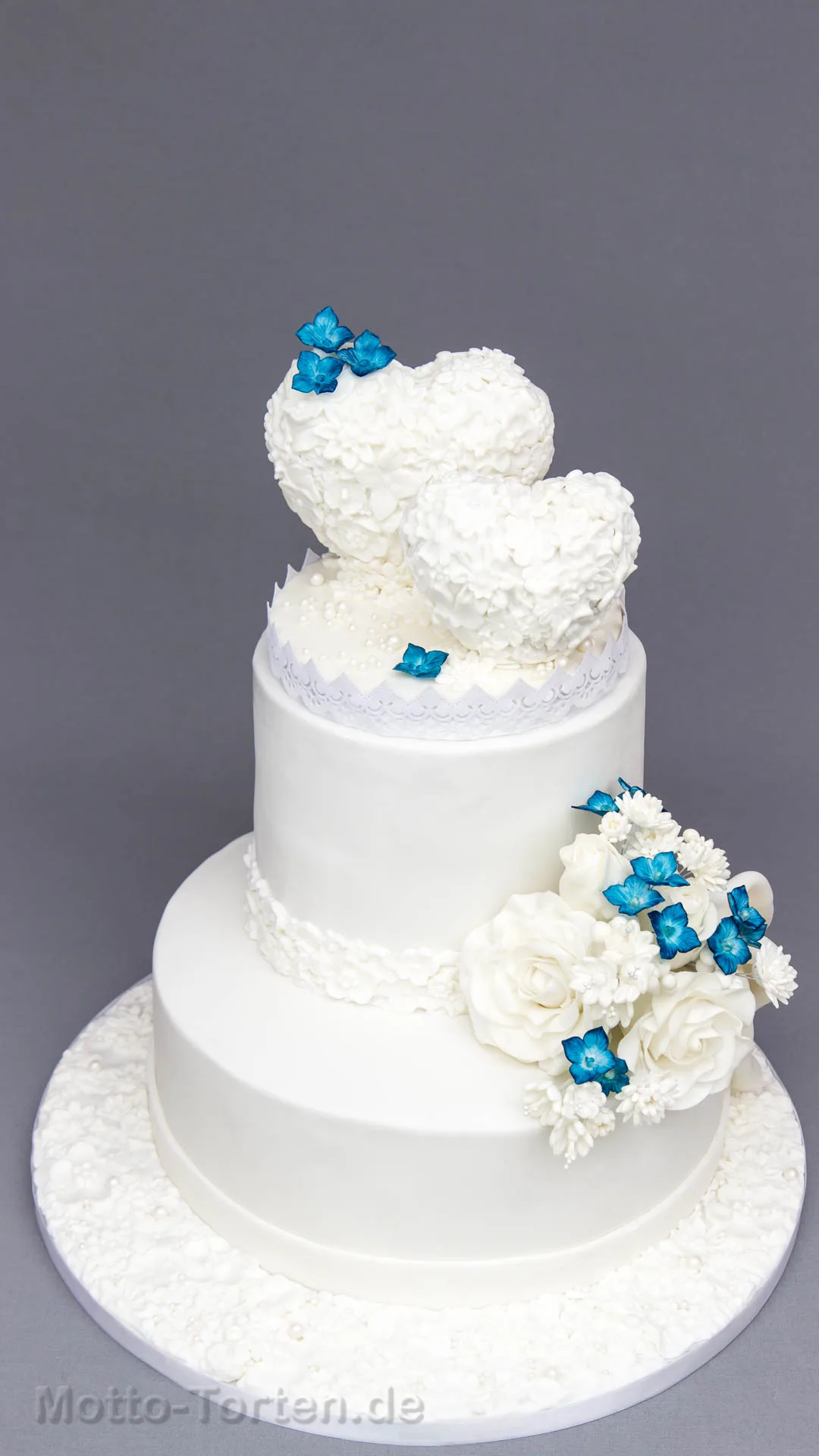 Hochzeitstorte mit zwei Herzen in einem Meer aus Zuckerblüten