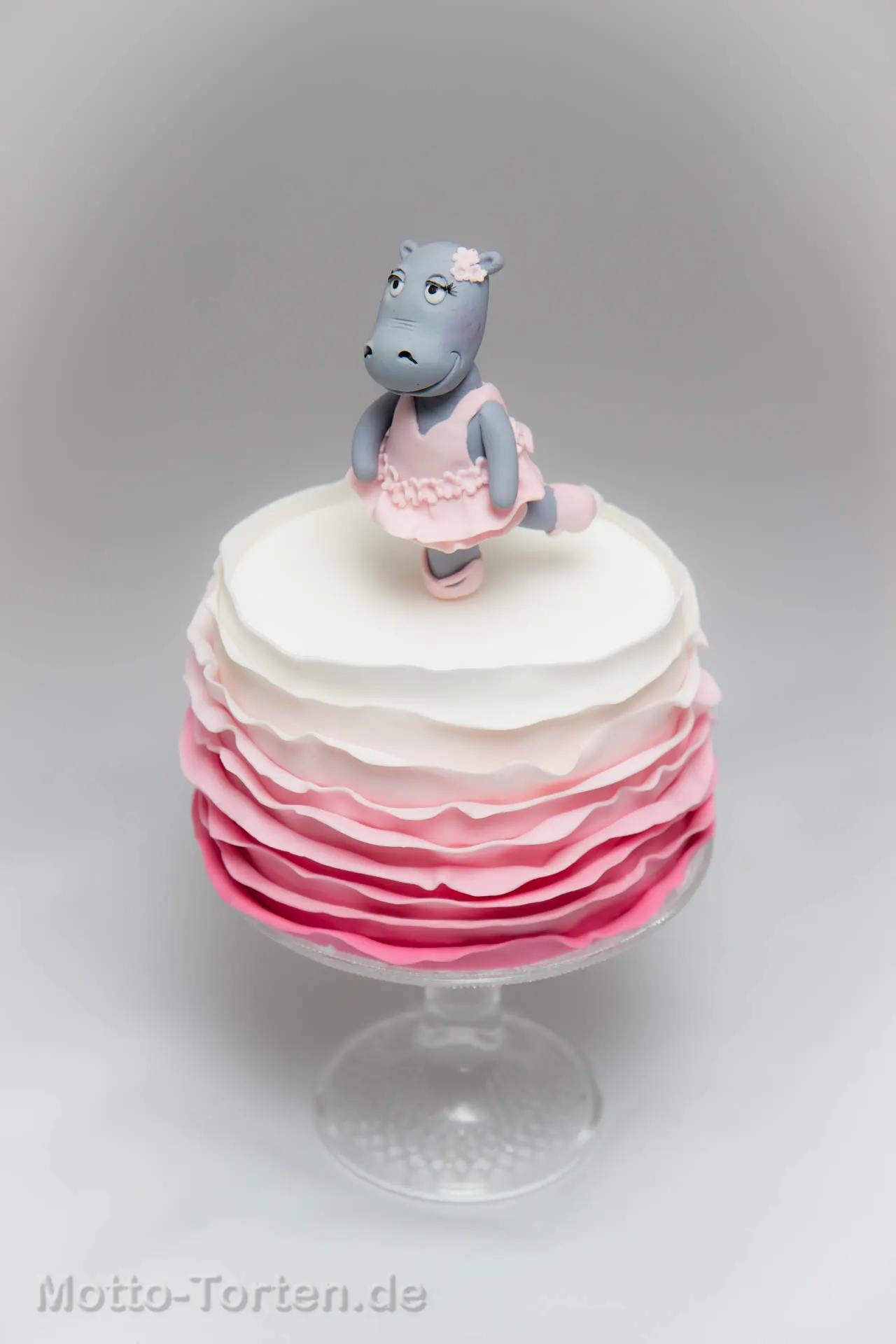 Torte mit rosa-weißem Rüschenverlauf aus Fondant, obenauf ein handmodelliertes Nilpferd im rosa Tütü mit Ballettschläppchen