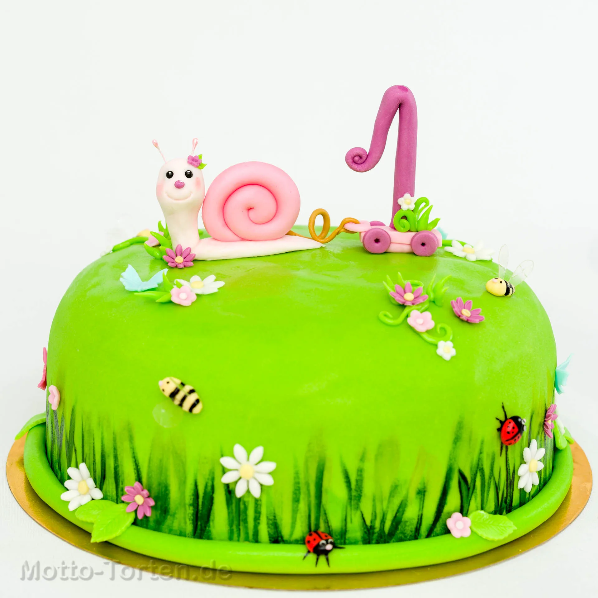 Torte als grüne Blumenwiese: eine rosa Schnecke zieht die Eins auf einem Wagen hinter sich her, dazu Marienkäfer, Bienen und Blüten
