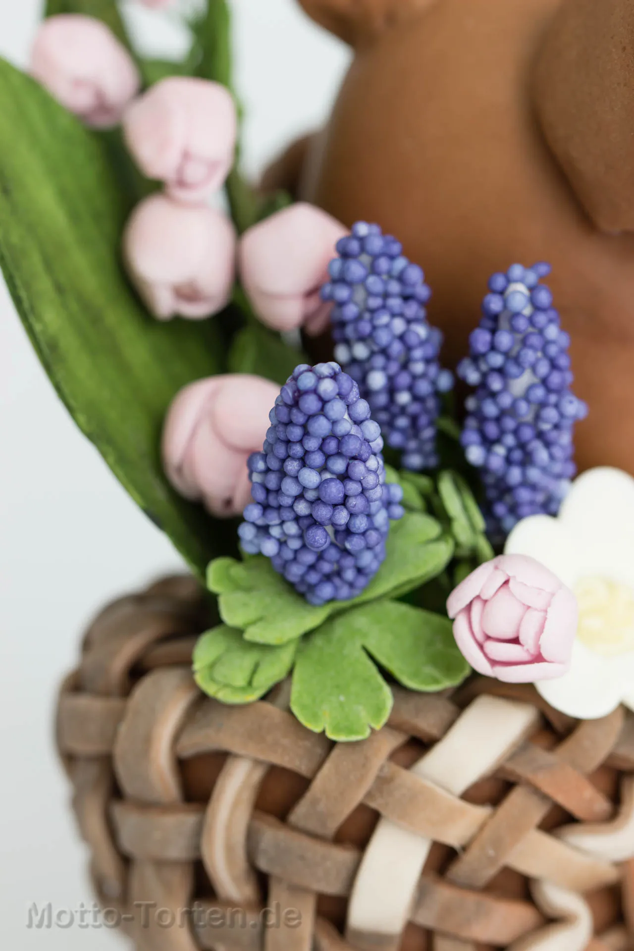 Blaue Fantasieblumen aus Blütenpaste an Draht, mit blauen Zuckerperlen besetzt, dazu grüne Blätter
