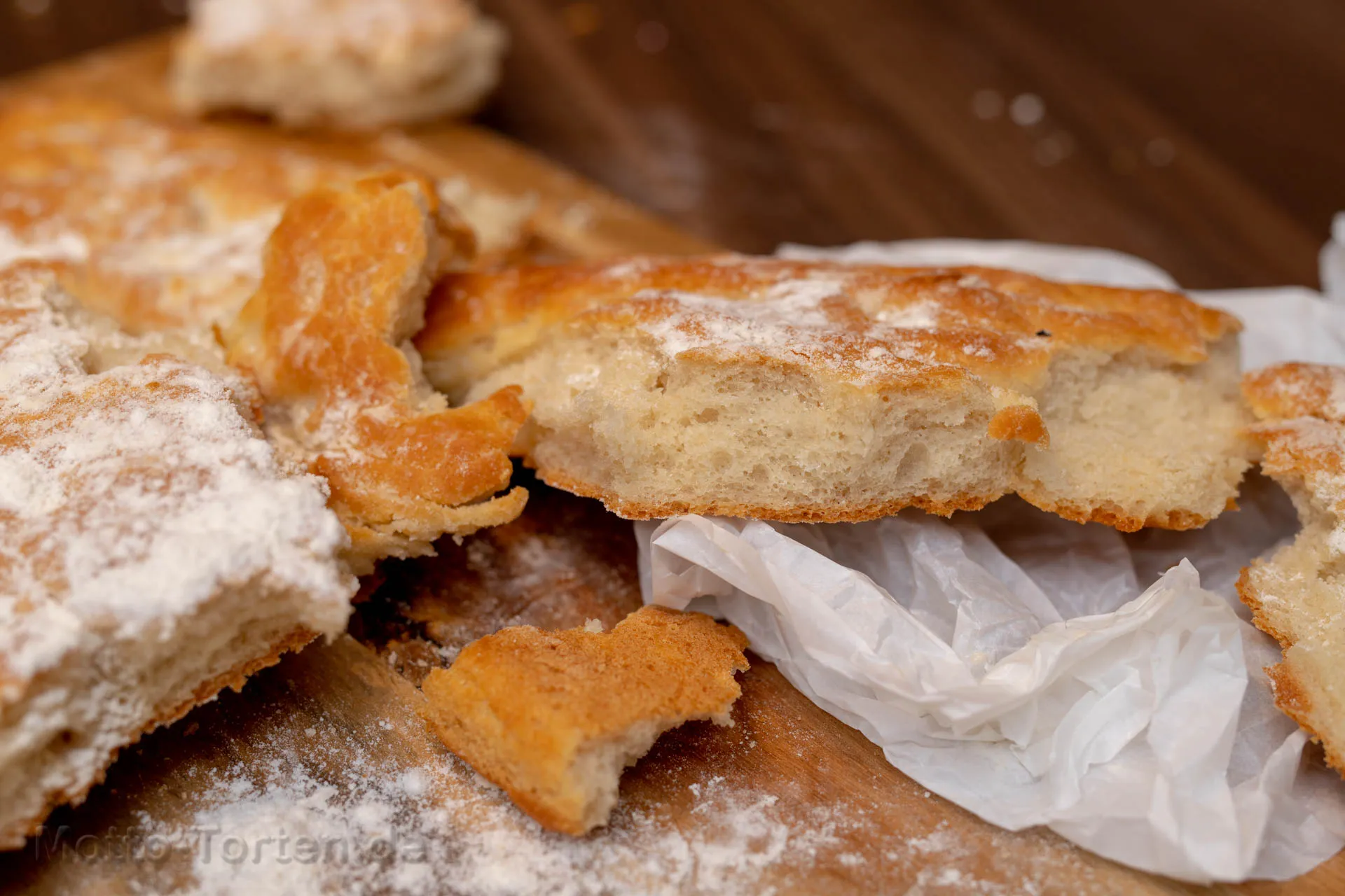 Aufgeschnittenes Pizzabrot vom Blech, goldbraun gebacken und mit Kräutern bestreut