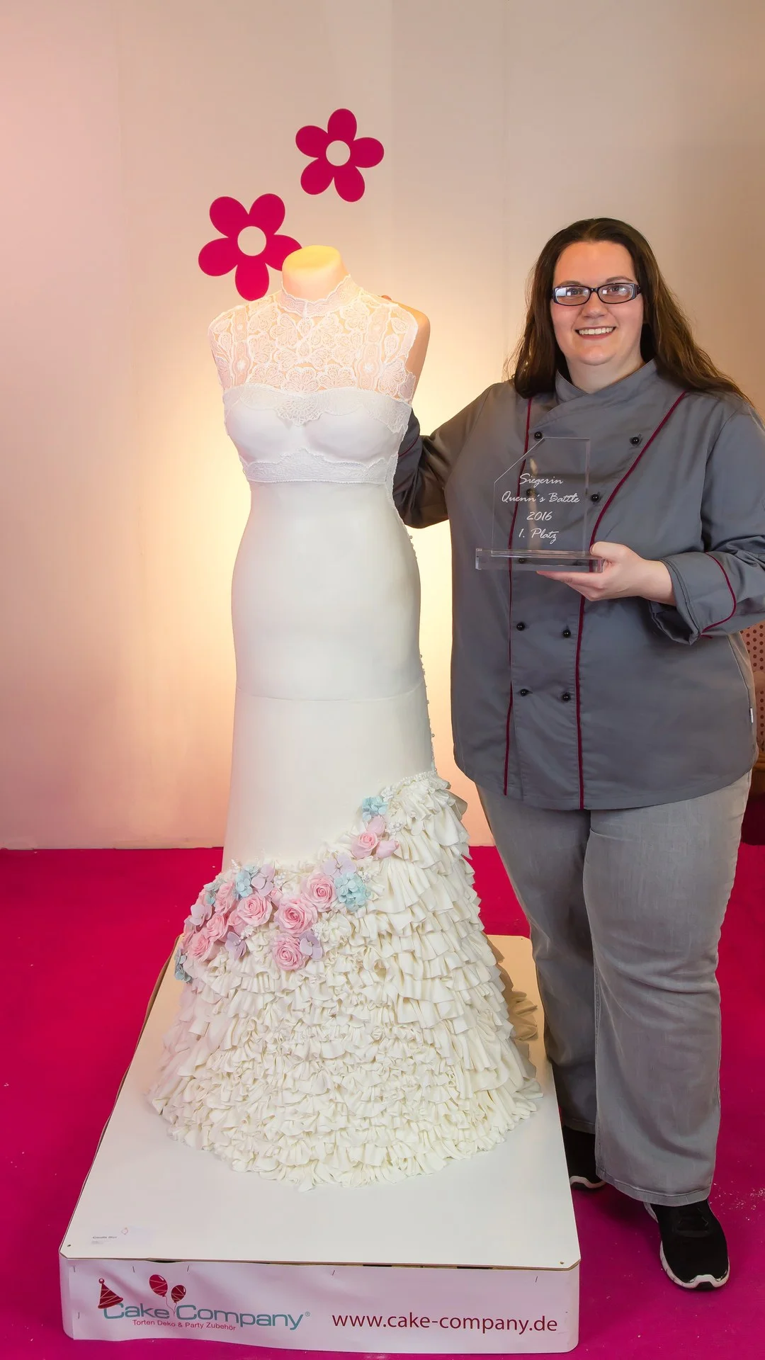 Claudia im Kochjacket mit dem Siegerpokal neben ihrem lebensgroßen essbaren Brautkleid