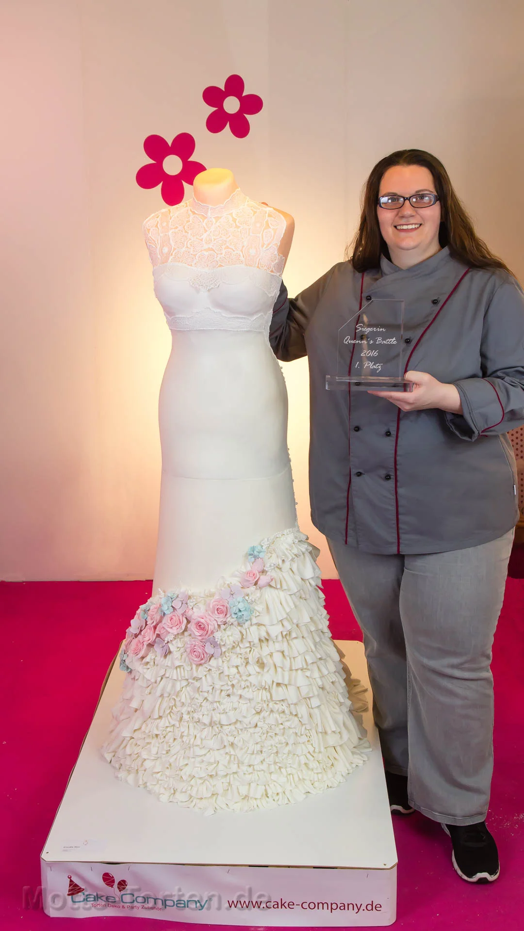 Claudia im Kochjacket mit dem Siegerpokal neben ihrem lebensgroßen essbaren Brautkleid