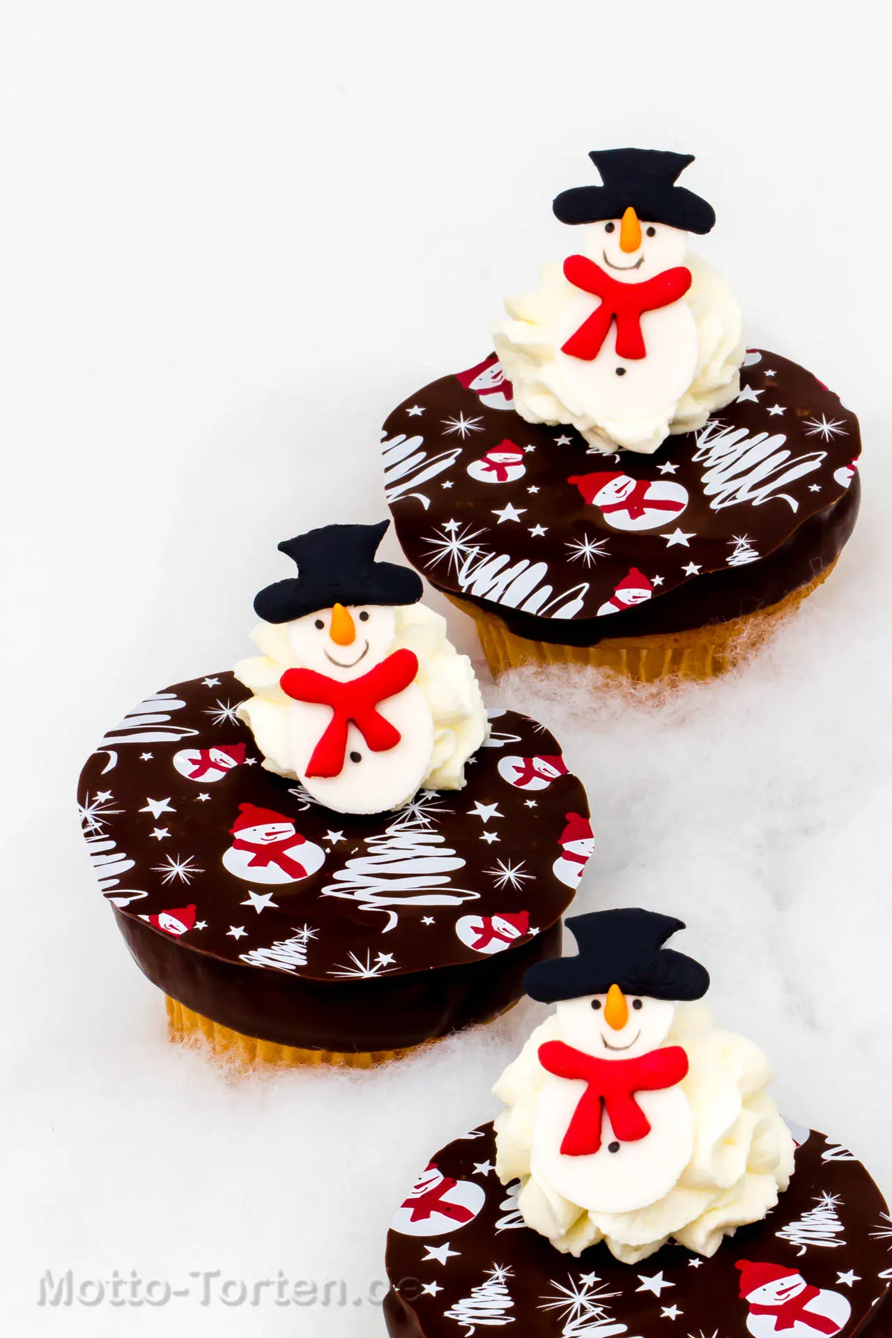 Cupcakes mit weihnachtlichem Schokoladenaufleger und modelliertem Schneemann mit Zylinder