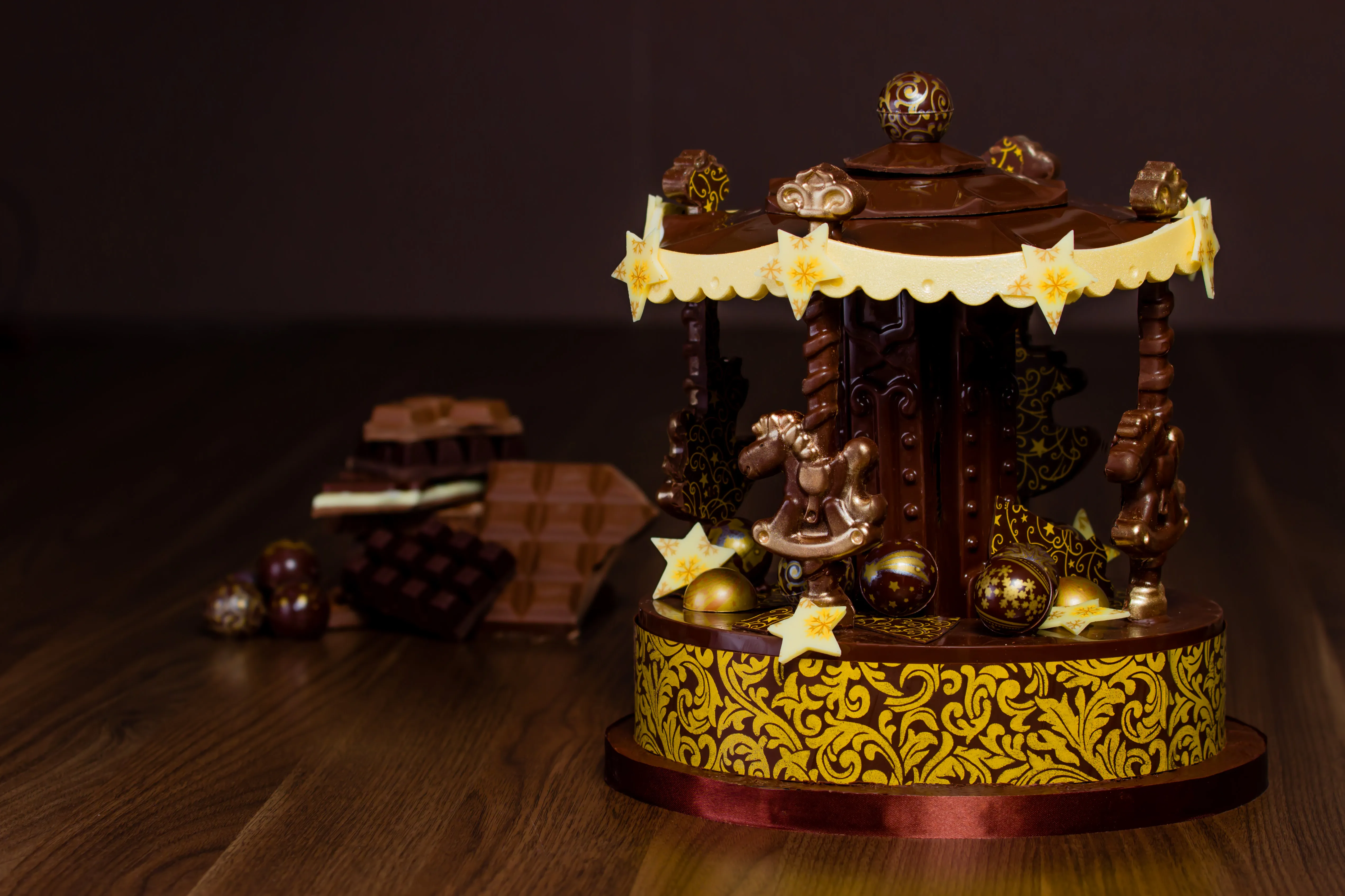 Karussell aus Schokolade mit vier Pferdchen, goldener Bordüre und Pralinen, auf einer Tortenplatte