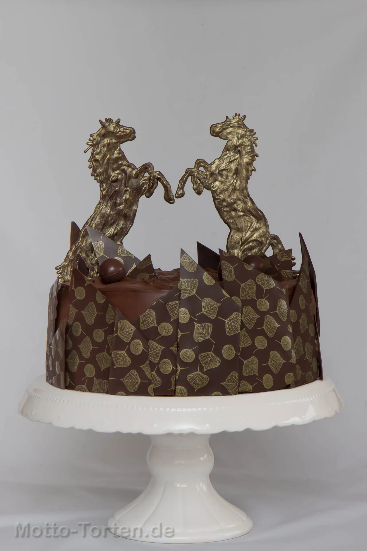 Schokoladensahnetorte mit aufgespritzten Pferden aus Schokolade und Schokoladenrand