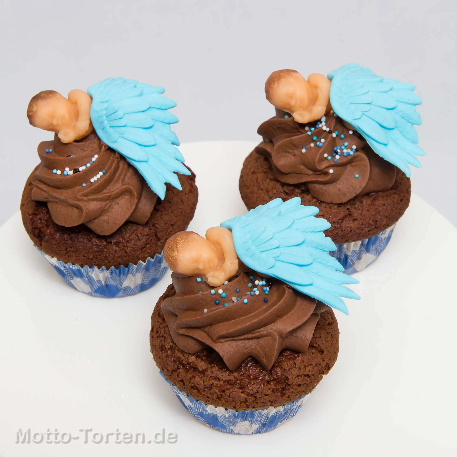Schokoladen-Cupcakes mit modellierten schlafenden Babys und hellblauen Engelsflügeln