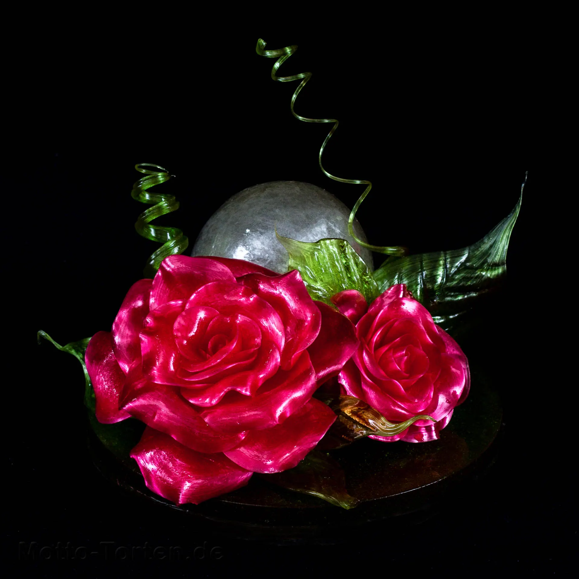 Schaustück aus gezogenem Zucker: pinkfarbene Rosen und Knospen mit grünen Blättern und Spiralen vor einer geblasenen Zuckerkugel