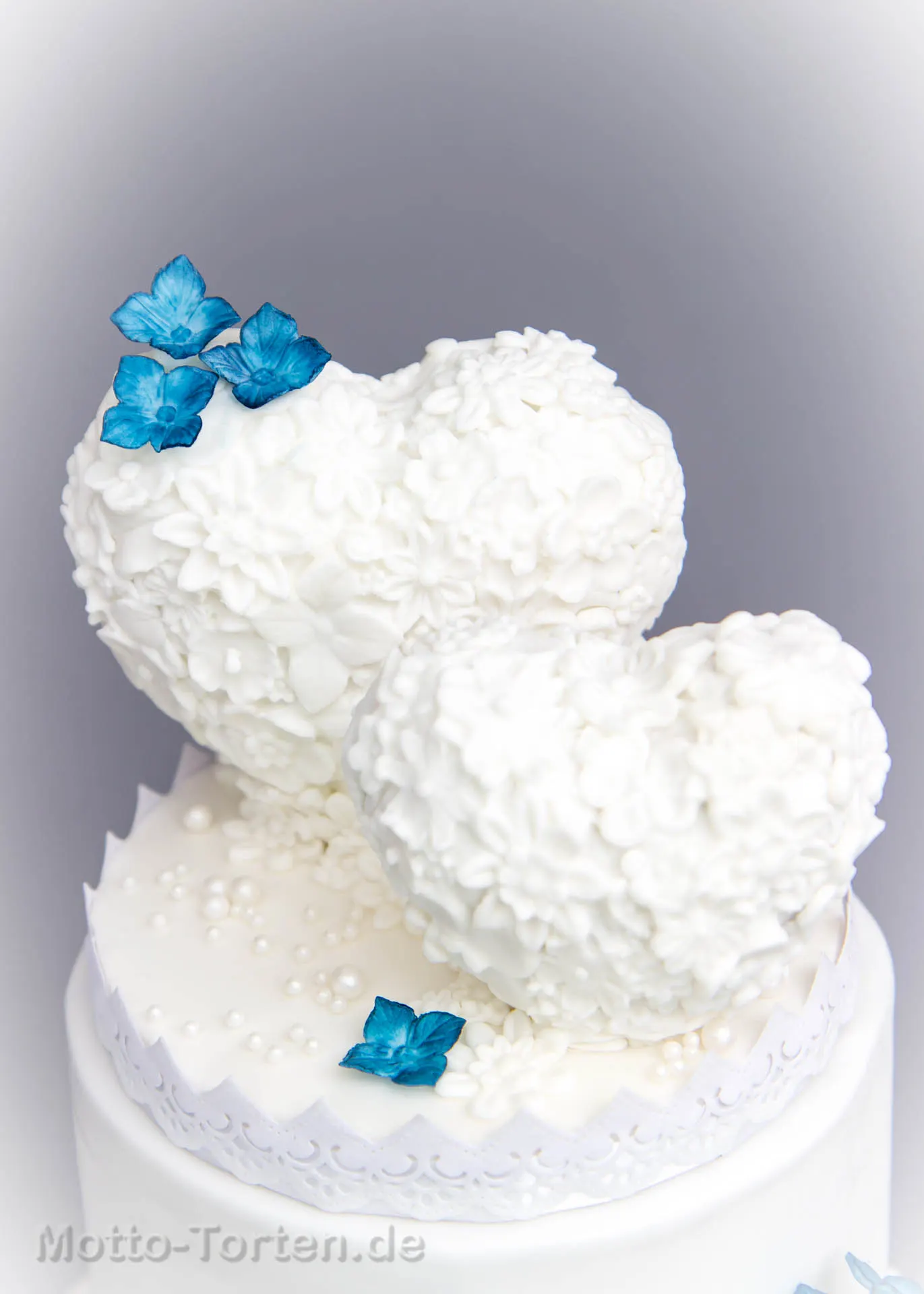 Hochzeitstorte mit zwei Herzen in einem Meer aus Zuckerblüten – Ansicht 2