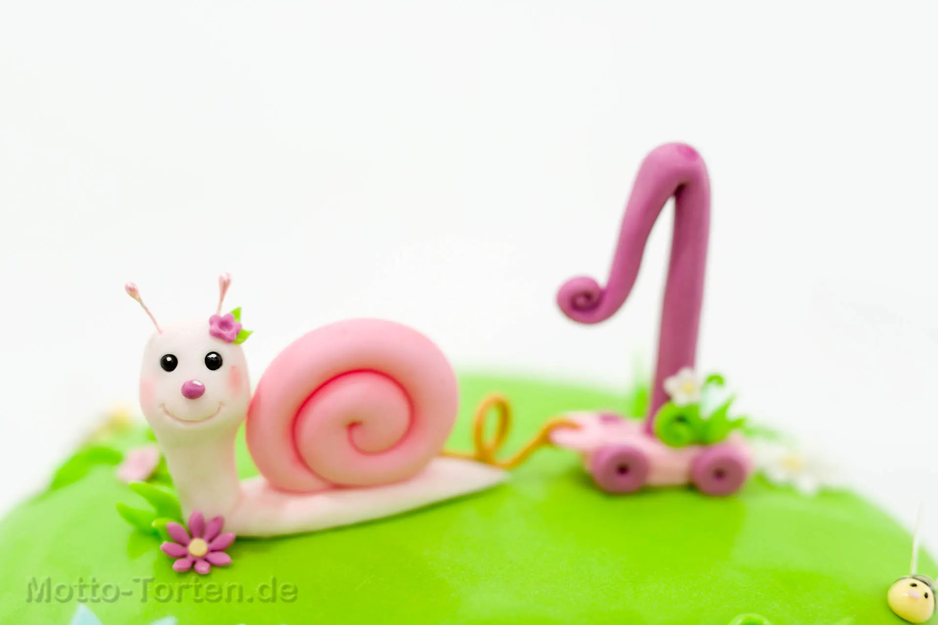 Torte als grüne Blumenwiese: eine rosa Schnecke zieht die Eins auf einem Wagen hinter sich her, dazu Marienkäfer, Bienen und Blüten – Ansicht 2
