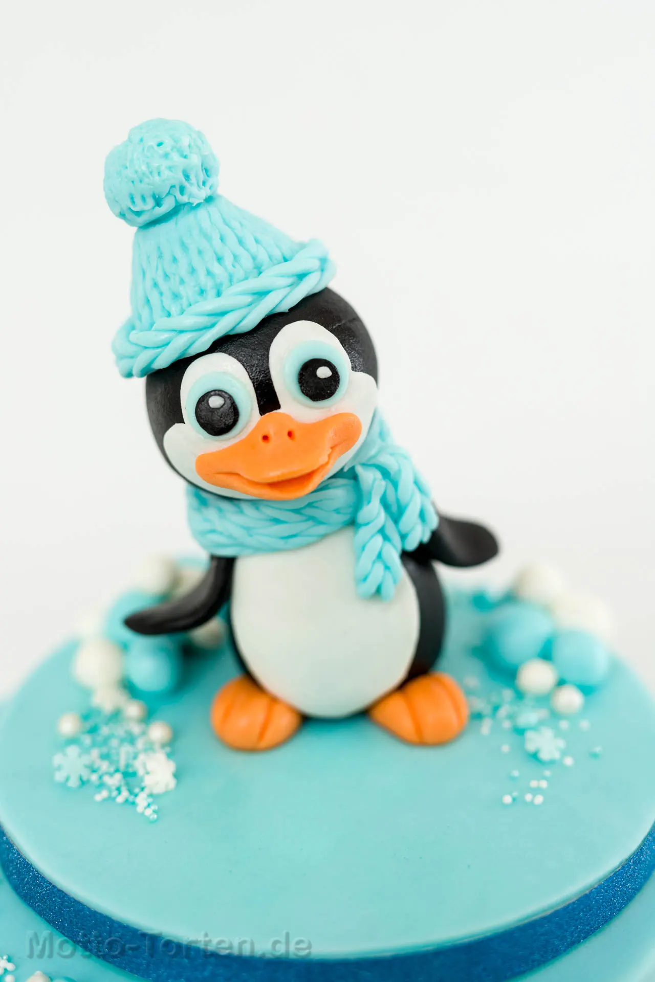 Zweistöckige babyblaue Torte mit handmodelliertem Pinguin und Schneeflocken aus essbarer Spitze – Ansicht 2