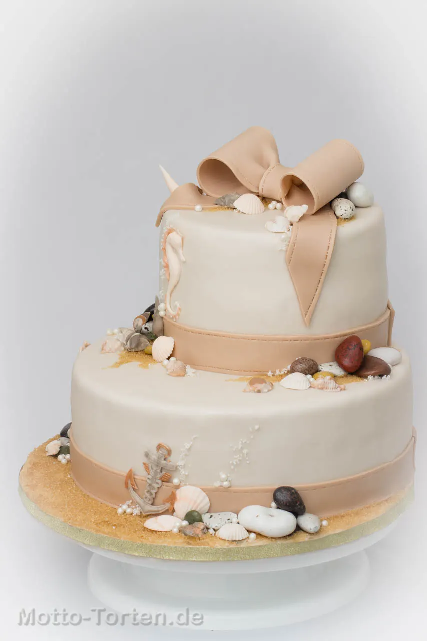 Nougat und cremefarbene Hochzeitstorte mit essbaren Muscheln, Seepferdchen und Sand