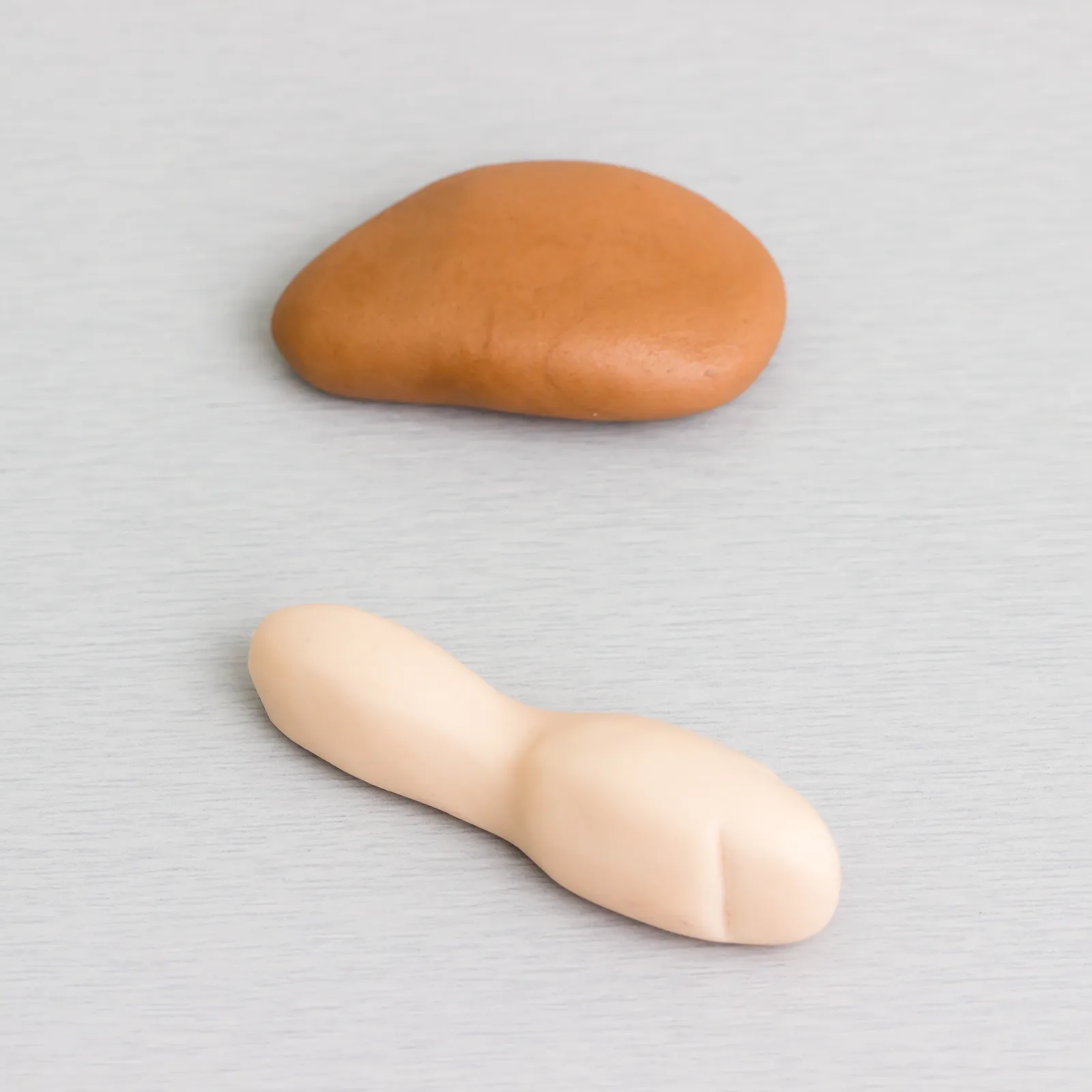 Ein brauner Tropfen für den Oberschenkel und ein beiger Strang für den Fuß, nebeneinander gelegt