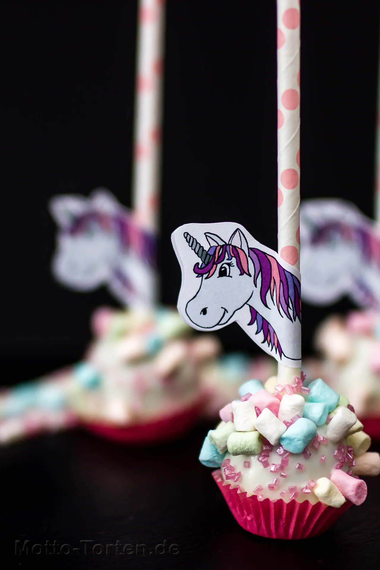 Cake Pops mit aufgesteckten Einhornköpfen aus Papier, dazwischen Marshmallows