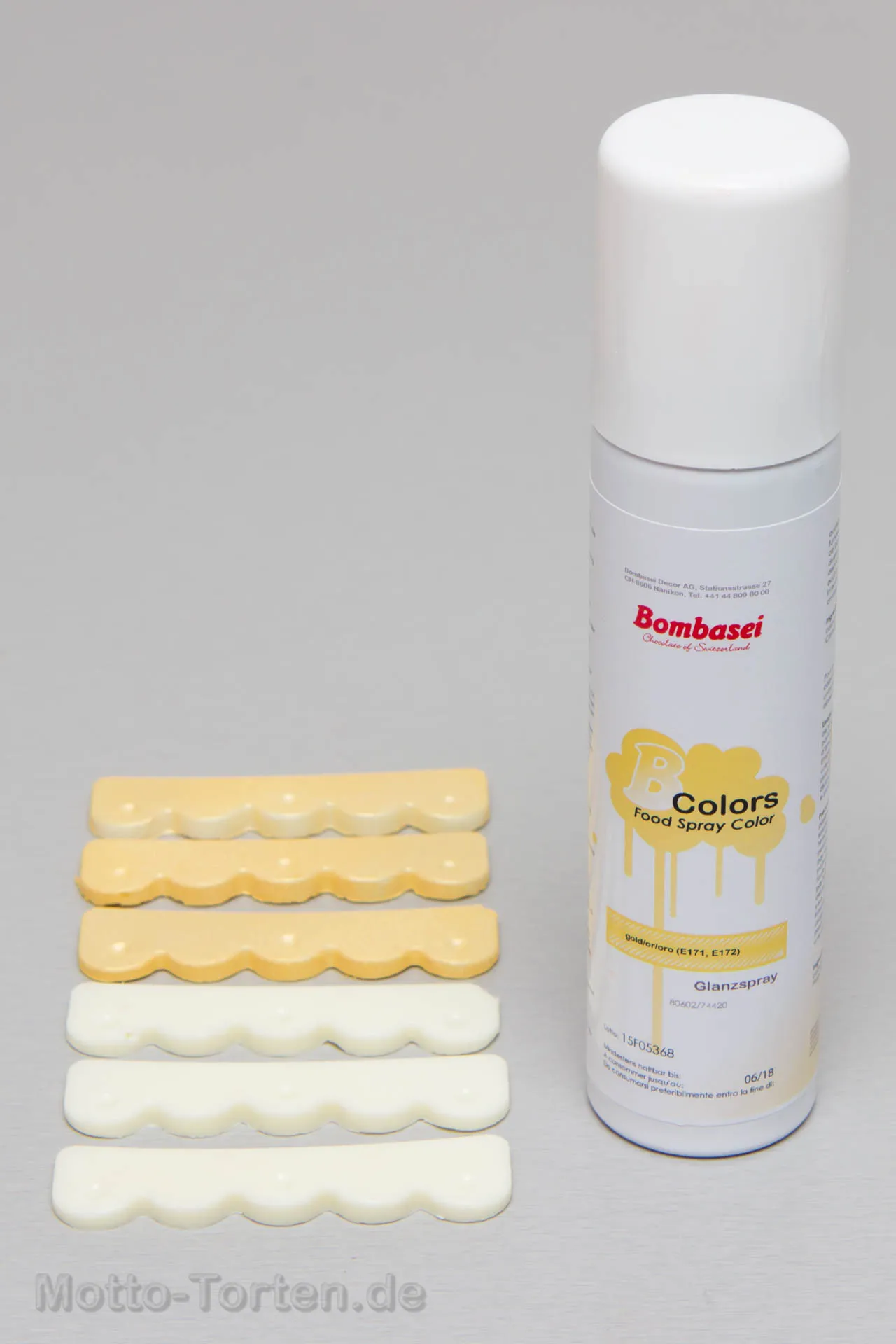 Die weißen Bordürenstücke, teils mit Gold besprüht, neben der Sprühfarbe