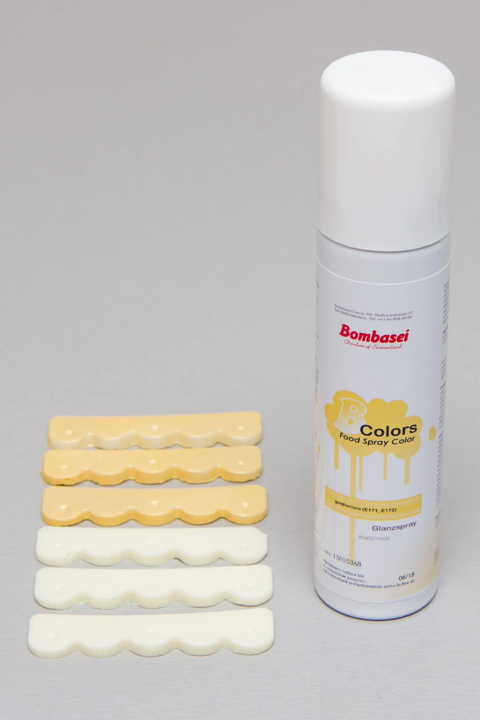 Die weißen Bordürenstücke, teils mit Gold besprüht, neben der Sprühfarbe