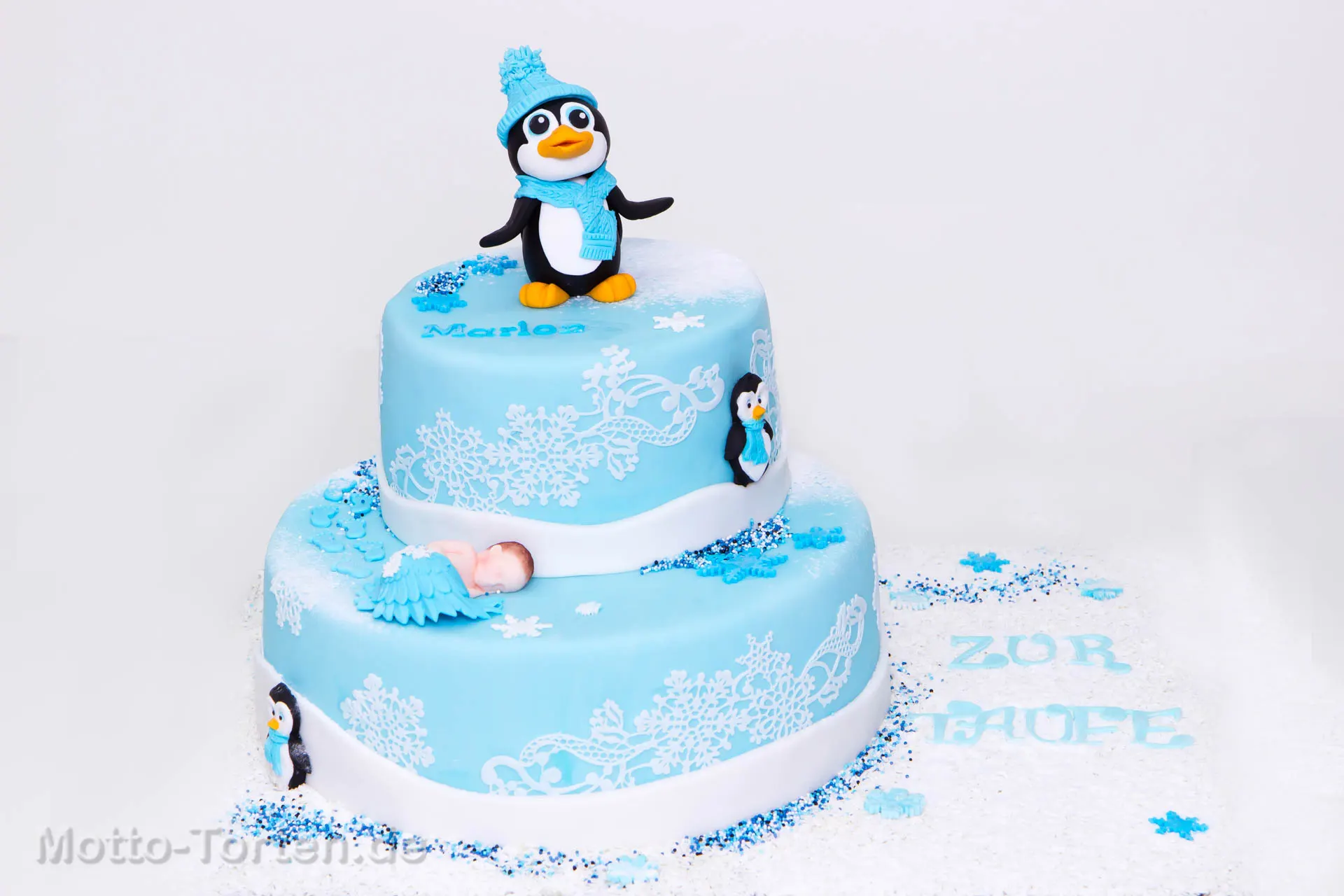 Handmodellierter Pinguin mit blauer Strickmütze und Schal auf einer hellblauen Tauftorte, daneben Schneeflocken und der Name Marlon – Ansicht 6