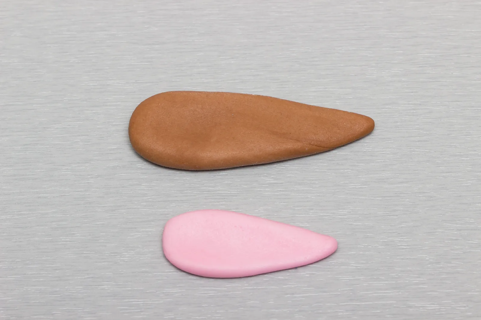 Ein brauner und ein rosa Tropfen für ein Ohr, nebeneinander gelegt